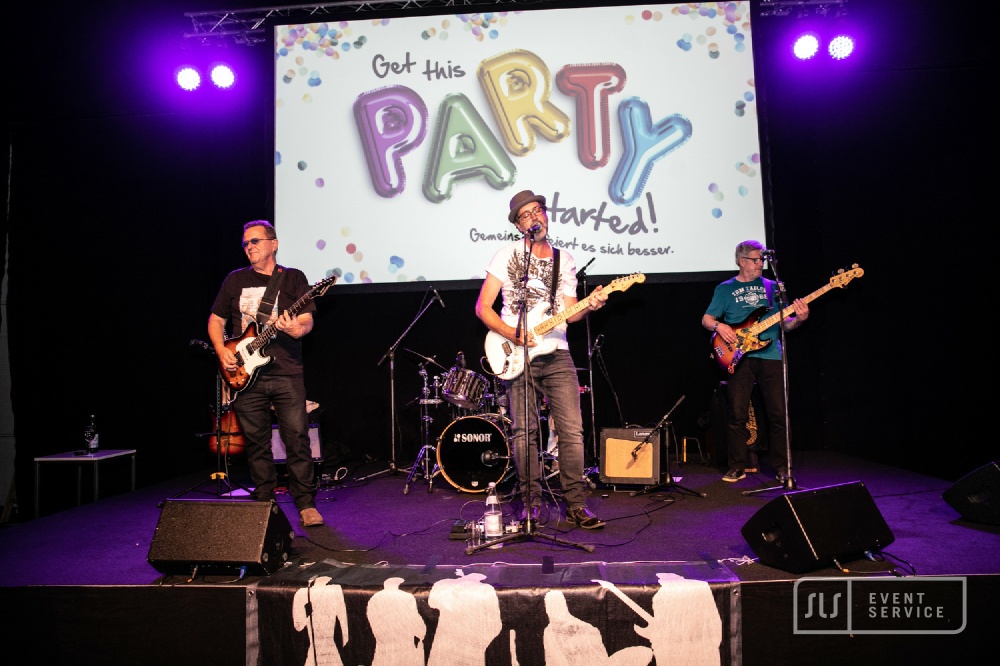 Live-Band mit Gitarren und Schlagzeug bei einem Konzert auf beleuchteter Bühne
