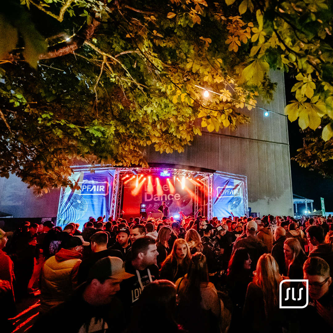 Dichtes Publikum vor rot beleuchteter Free-Dance-Bühne beim ZipfAir unter Bäumen am Abend
