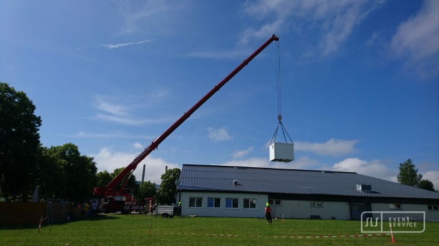 Kran hebt Eventcontainer für eine Veranstaltung über ein Gebäude bei der Umsetzung durch SLS Eventservice