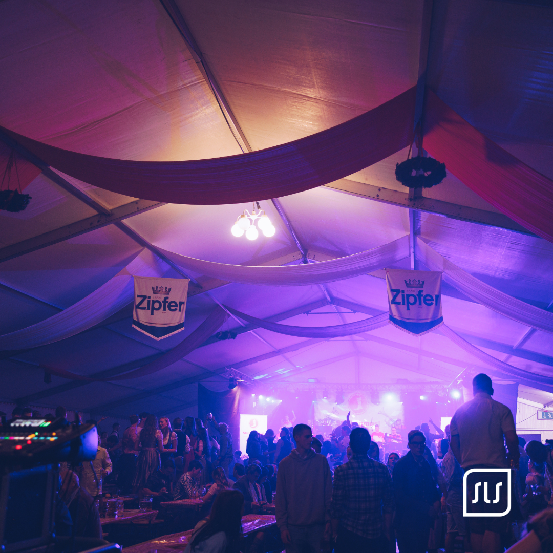 Gäste im Festzelt des Schiedlberger Oktoberfests vor violett beleuchteter Bühne und Zipfer-Bannern