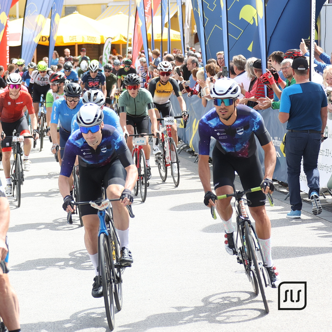 Großes Feld von Rennradfahrern fährt beim Start des 24-Stunden-Radmarathons in Grieskirchen durch die Zuschauerzone