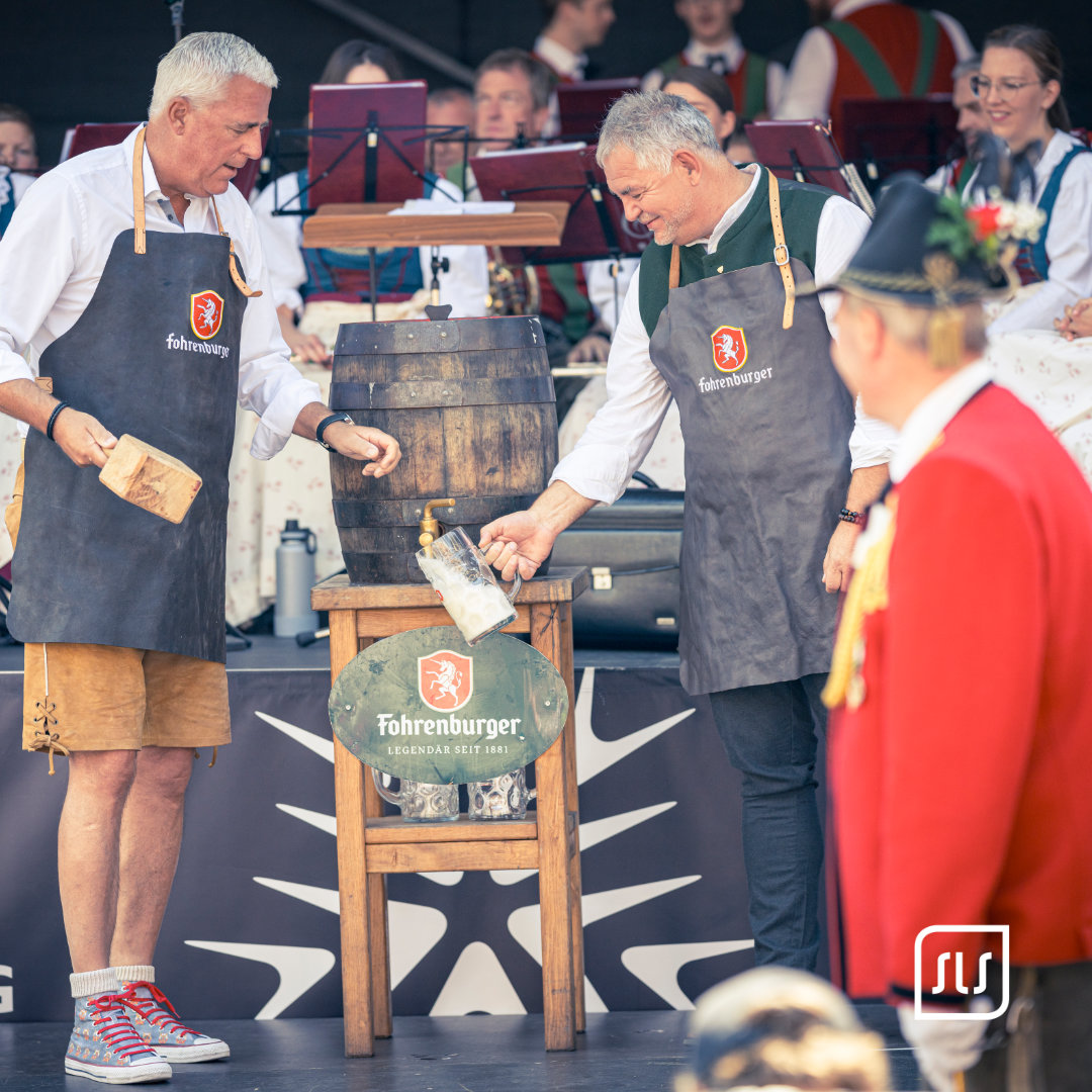 Zwei Männer am Bierfass auf der Dorffest-Bühne in St. Anton; einer füllt einen Krug am Zapfhahn