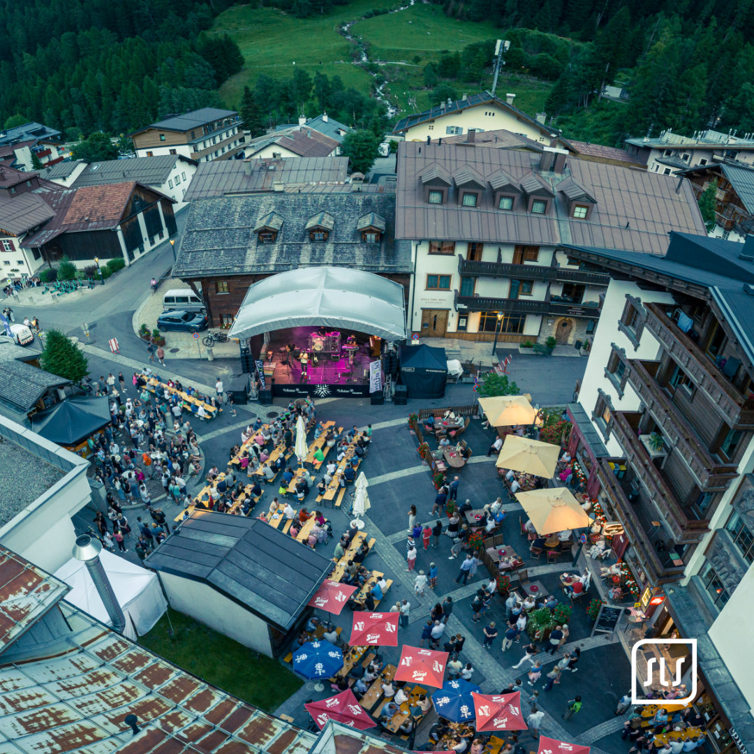 Blick von oben auf die Dorffest-Bühne, lange Festtische und Besucher in St. Anton am Arlberg