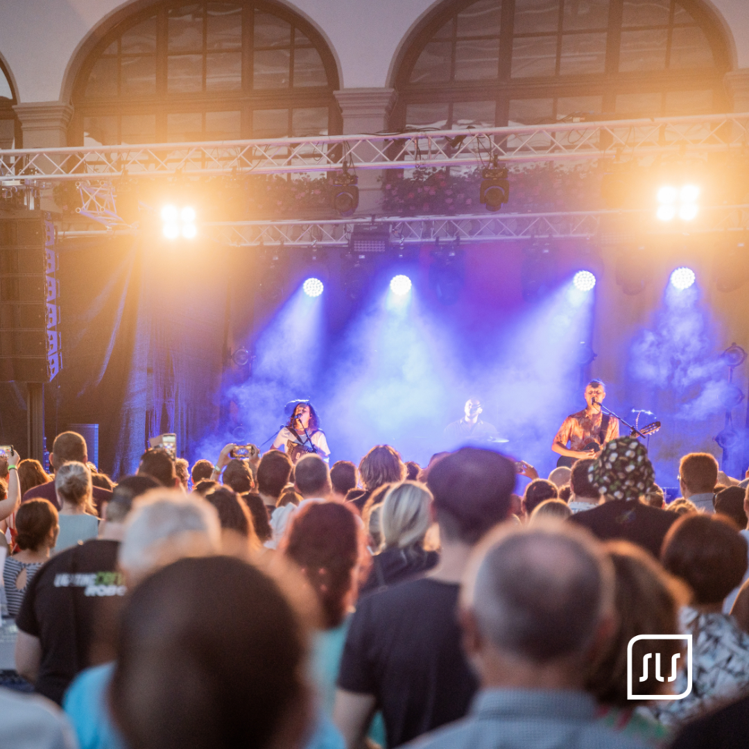 Band spielt auf blau beleuchteter Bühne vor dichtem Publikum beim Schlosscafé Sierning