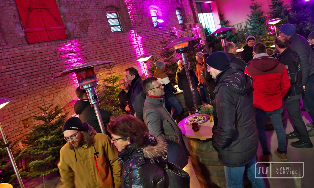 Gäste bei einem winterlichen Firmenevent in einer stimmungsvoll beleuchteten Halle