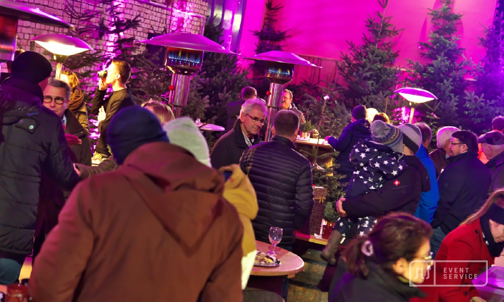 Gäste bei einem winterlichen Firmenevent mit Tannenbäumen und stimmungsvoller Beleuchtung