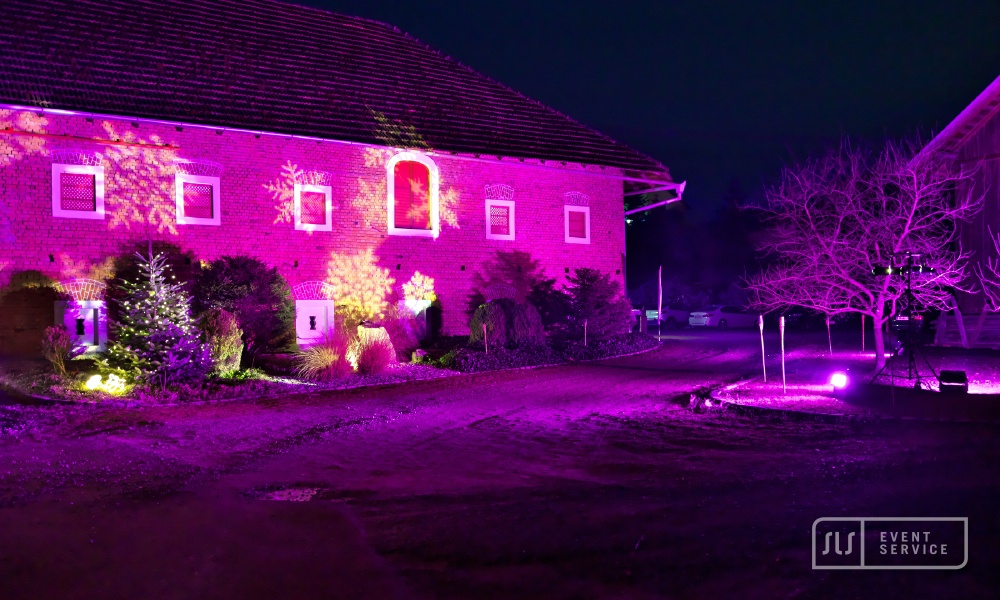 Historisches Gebäude mit pink-violetter Eventbeleuchtung und winterlicher Dekoration