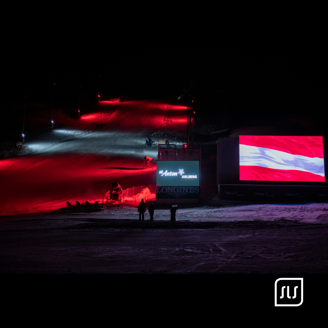 Rot und weiß beleuchtete Skipiste mit großer Videowand und österreichischer Flagge bei der JWSC-Eröffnung