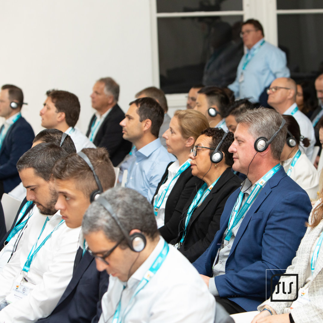 Konferenzgäste mit Kopfhörern sitzen in Reihen und verfolgen eine Präsentation bei der PAPCON 2023
