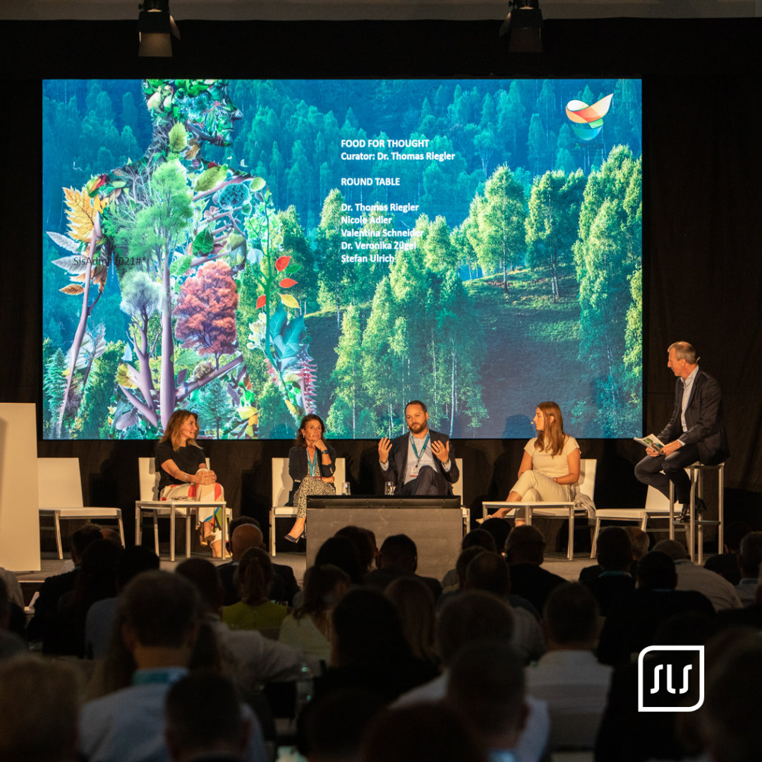 Fünf Personen diskutieren auf dem Podium der PAPCON 2023 vor einer großen Waldgrafik auf der Leinwand