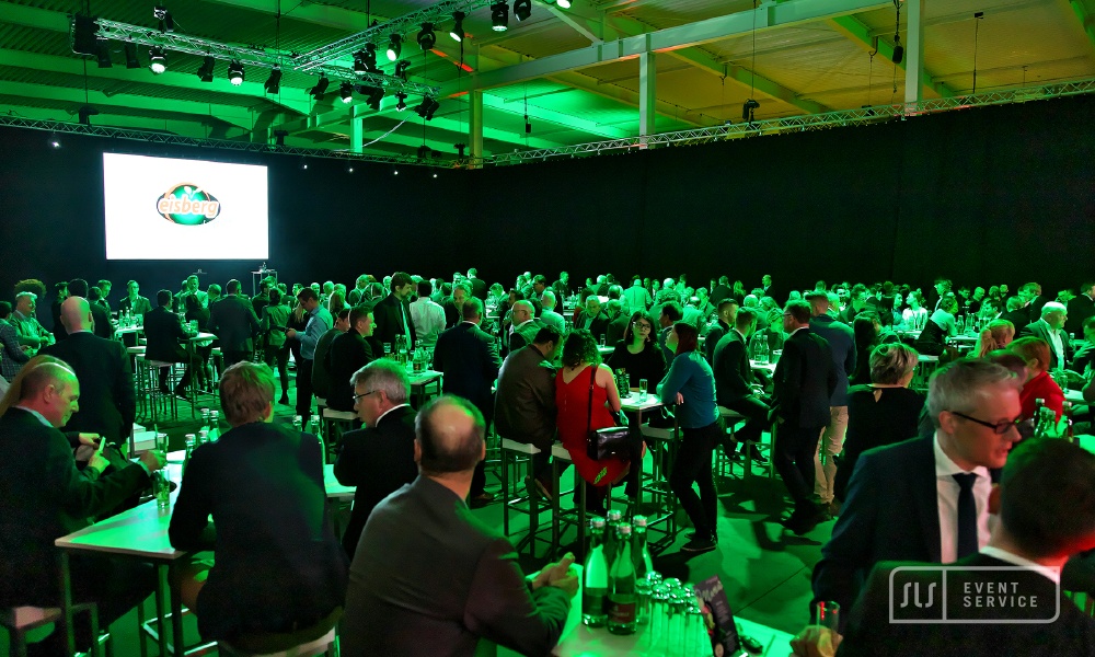 Gut besuchte Firmenveranstaltung mit zahlreichen Gästen an Stehtischen und grüner Eventbeleuchtung