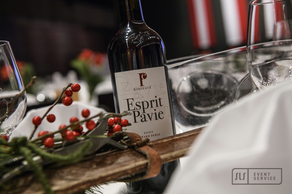 Rotweinflasche Esprit de Pavie auf festlich dekoriertem Tisch mit Weingläsern und winterlicher Dekoration