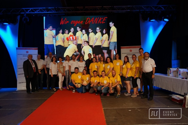 Mitarbeiterfest des Österreichischen Roten Kreuzes mit Teamfoto auf der Bühne und Veranstaltungstechnik von SLS Eventservice