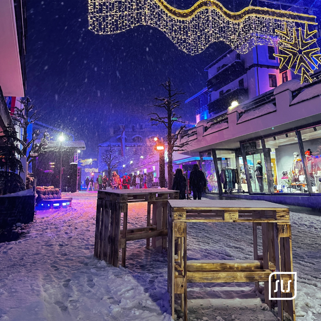 Verschneite Fußgängerzone in St. Anton bei Nacht mit Lichterketten und wenigen Passanten