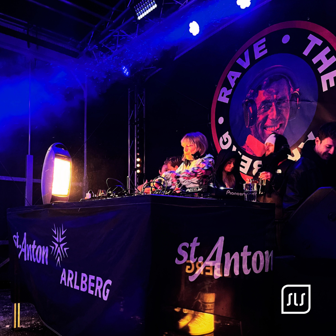 DJ steht am Mischpult auf der blau beleuchteten Rave-the-Arlberg-Bühne in St. Anton