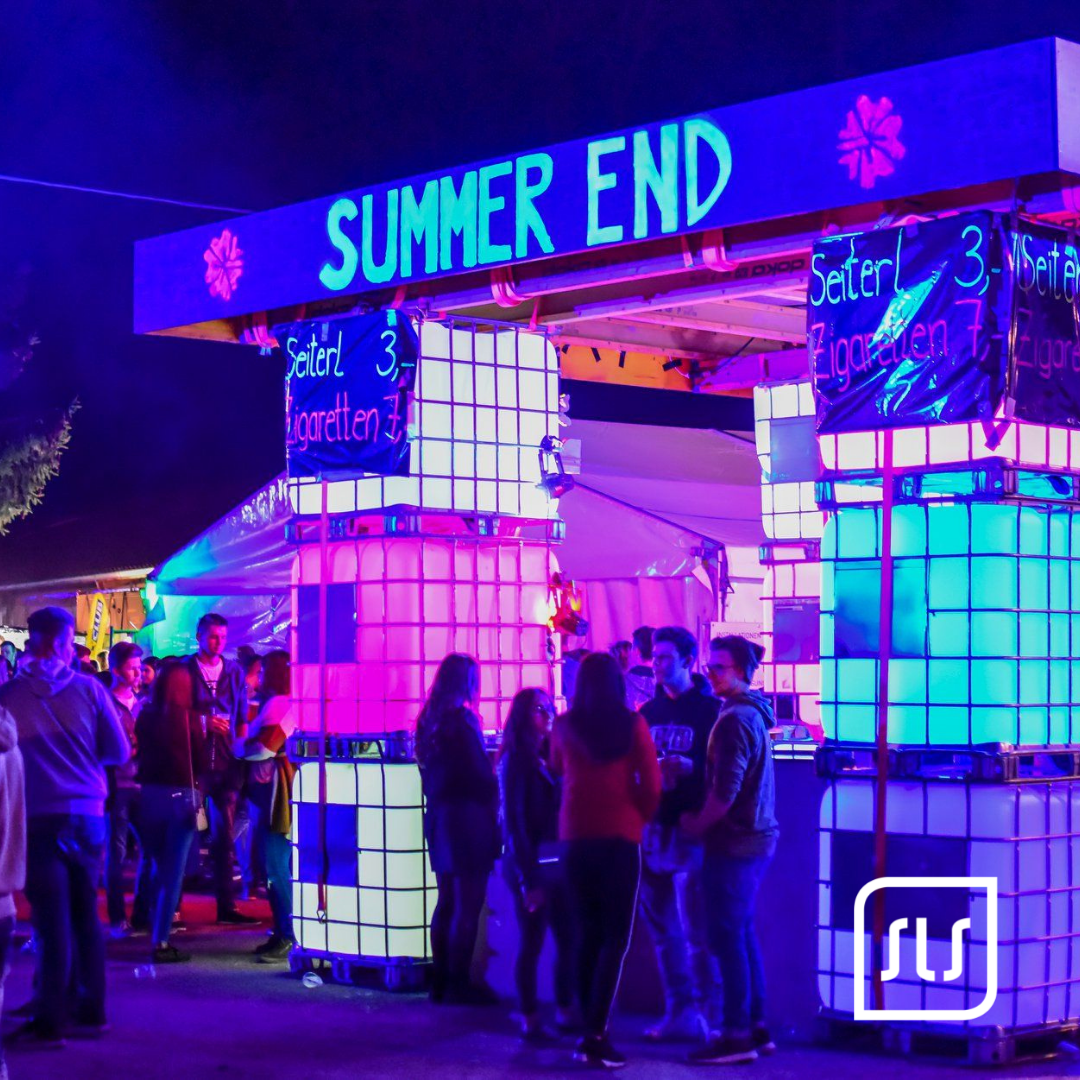 Beleuchteter Eingang mit Schriftzug „Summer End“ und Gästen bei einer nächtlichen Veranstaltung