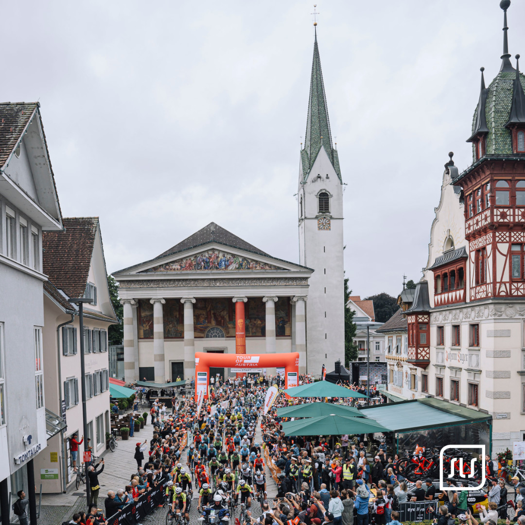 Großes Fahrerfeld und Publikum beim Start der Tour of Austria 2023 zwischen historischen Gebäuden in Dornbirn