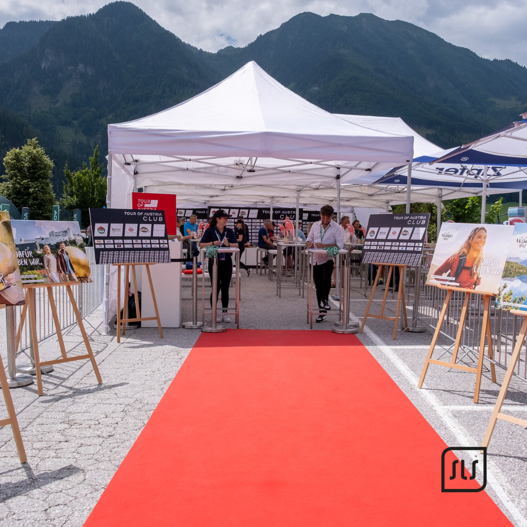 Roter Teppich führt zum weißen VIP-Club-Zelt der Tour of Austria 2023 vor einer Bergkulisse