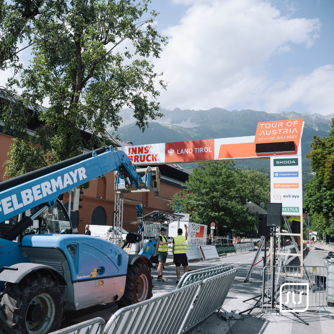Teleskoplader und Helfer beim Aufbau des Zielbogens der Tour of Austria 2023 in Innsbruck