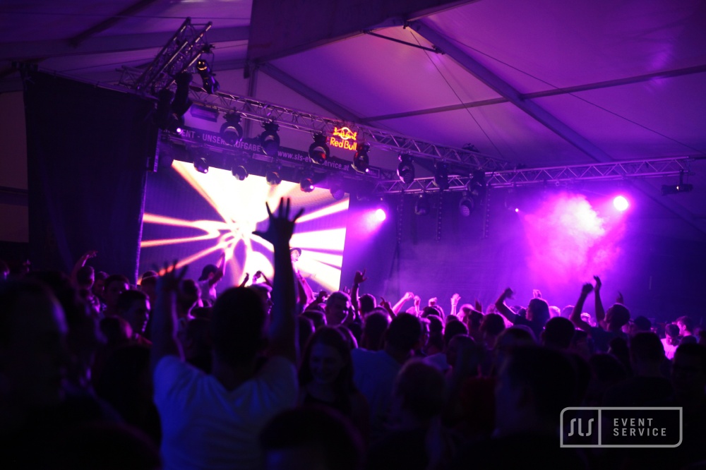 DJ auf einer Bühne vor großem Publikum mit pinker Lichtshow