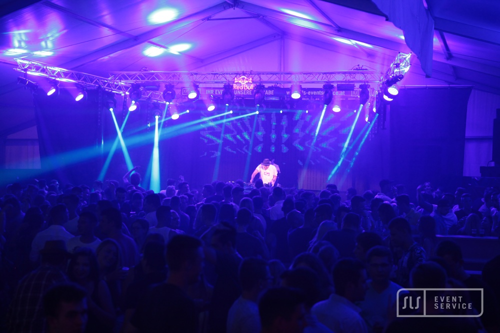 DJ auf einer Bühne vor großem Publikum mit blauer und violetter Lichtshow
