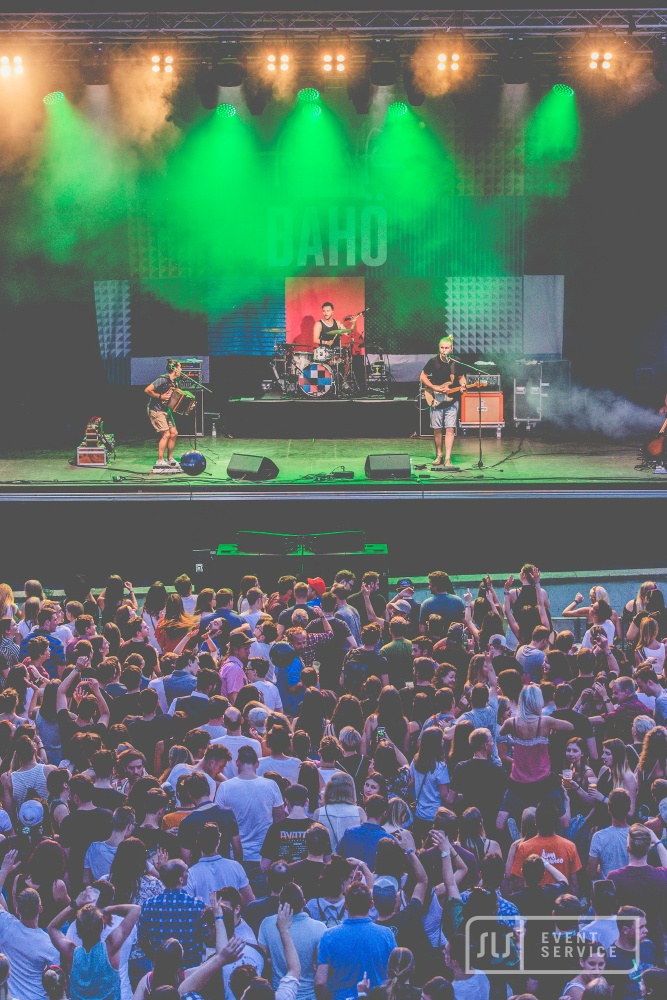 Live-Konzert mit Band auf großer Bühne, grünem Bühnenlicht und feierndem Publikum