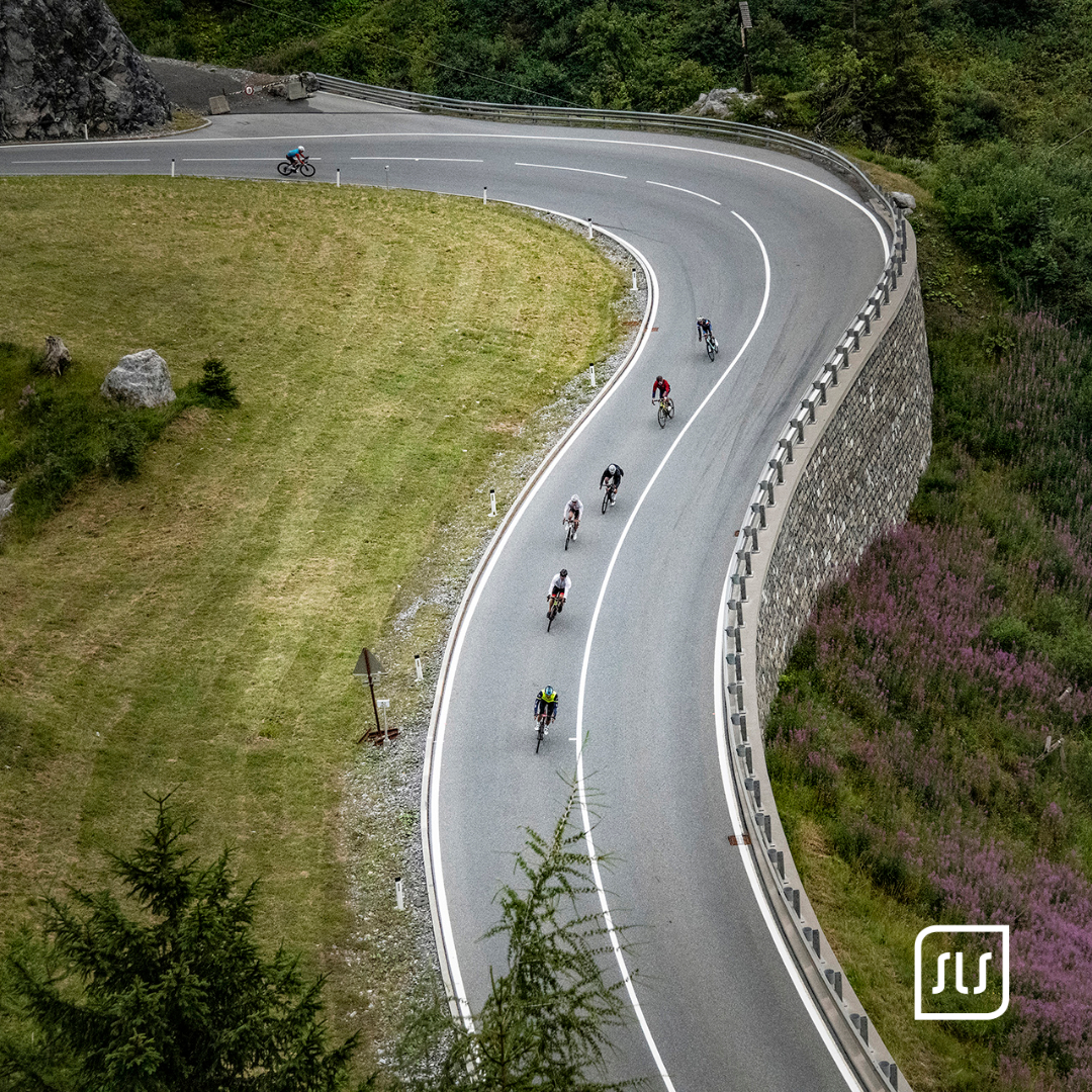 Blick von oben auf mehrere Rennradfahrende in einer weiten Bergkehre beim Arlberg Giro 2022