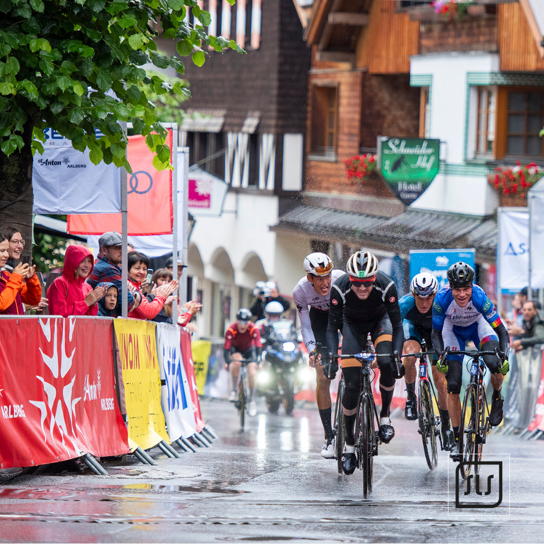 Vier Rennradfahrer fahren beim Arlberg Giro 2023 auf nasser Straße durch St. Anton am Arlberg
