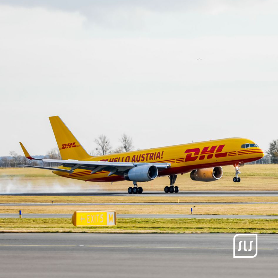 Gelb-rotes DHL-Flugzeug mit Schriftzug „Hello Austria!“ setzt auf einer Landebahn auf