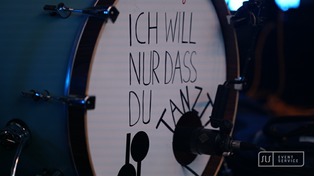 Nahaufnahme einer Bassdrum mit dem Schriftzug „Ich will nur dass du tanzt“ und einem Mikrofon davor