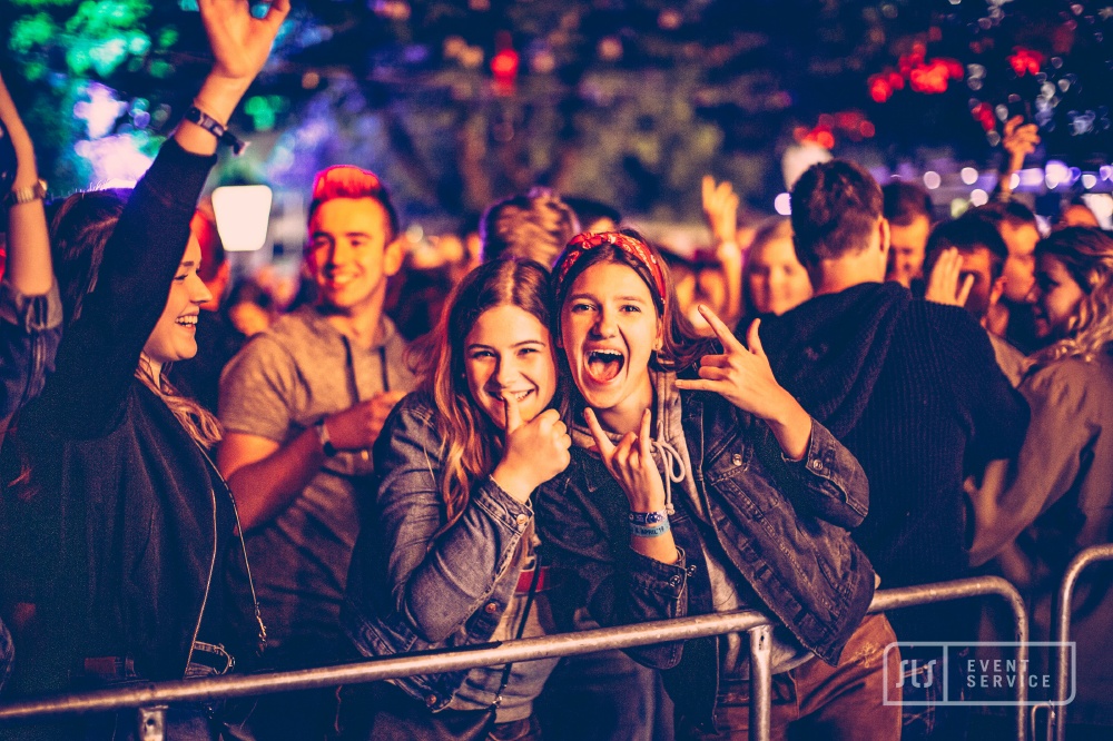 Junge Besucherinnen feiern ausgelassen bei einem Konzert