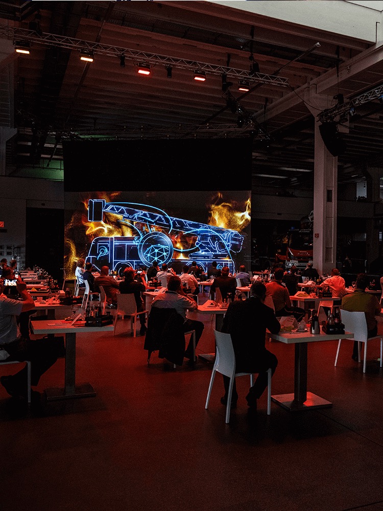 Publikum vor einer großflächigen Fahrzeugpräsentation mit Lichttechnik bei der Magirus Weltpremiere