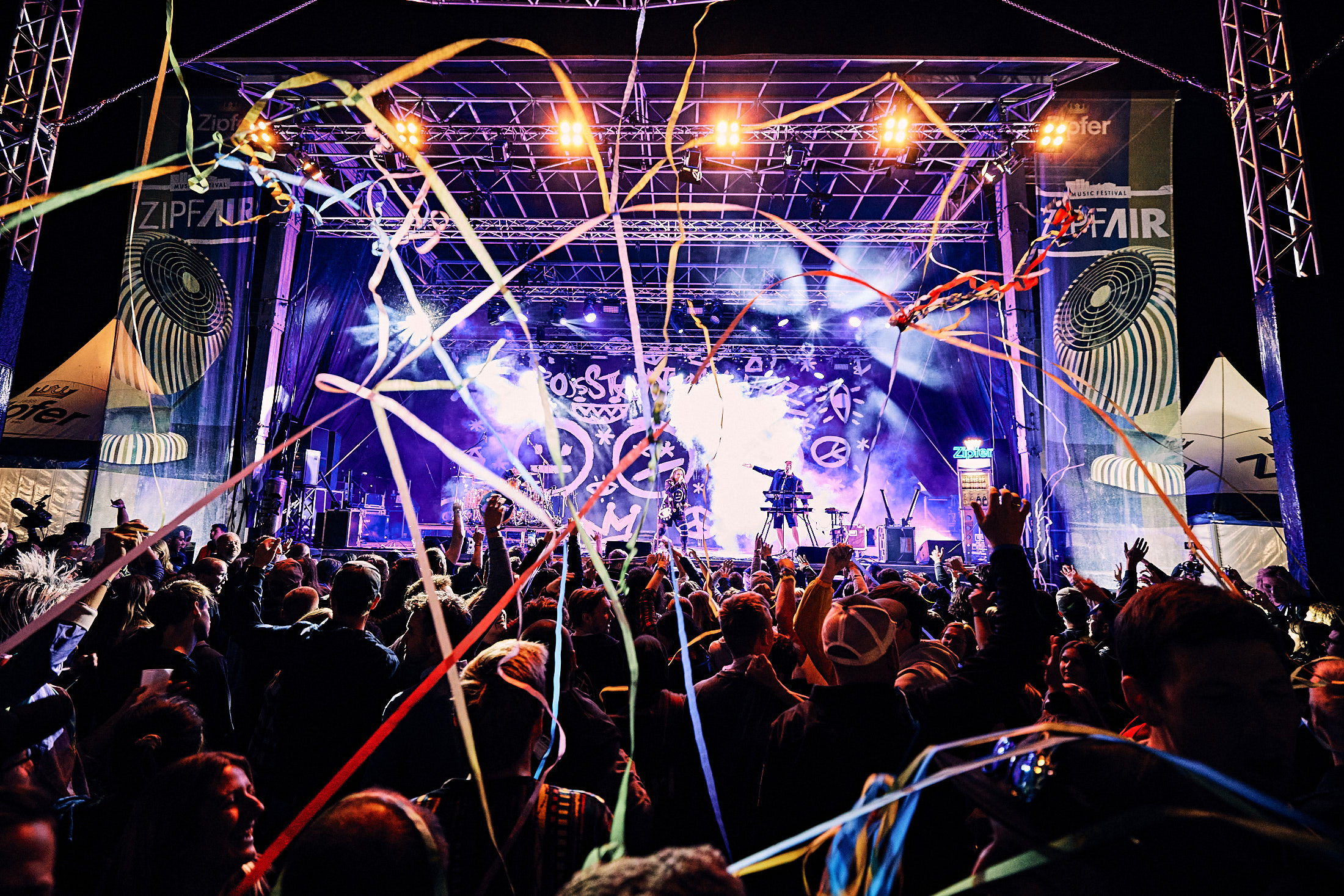 Beleuchtete Hauptbühne beim ZipfAir Festival mit Band, bunten Luftschlangen und jubelndem Publikum